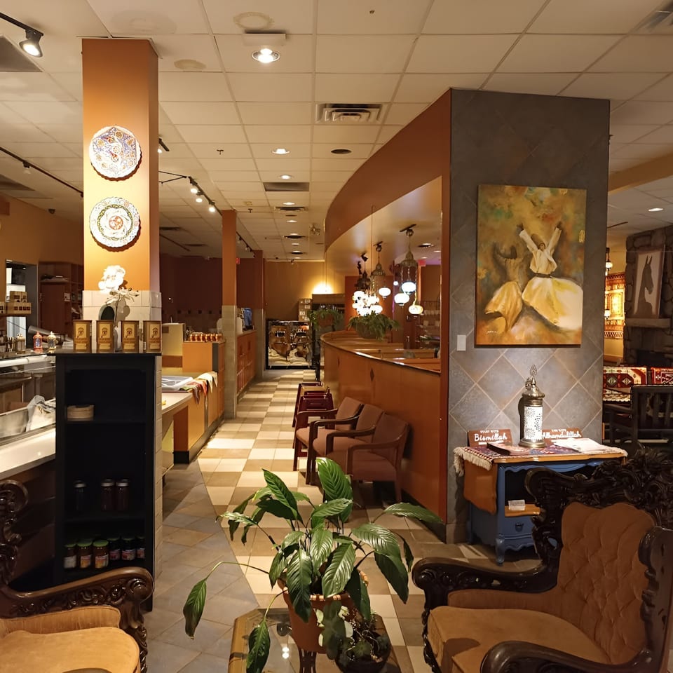 Interior of Kebab House/Mozaic Cafe with Turkish decor, seating, and a painting of a whirling dervish.