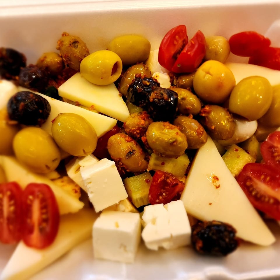 Close-up of a Turkish mezze platter with olives, feta, cheese slices, and cherry tomatoes.