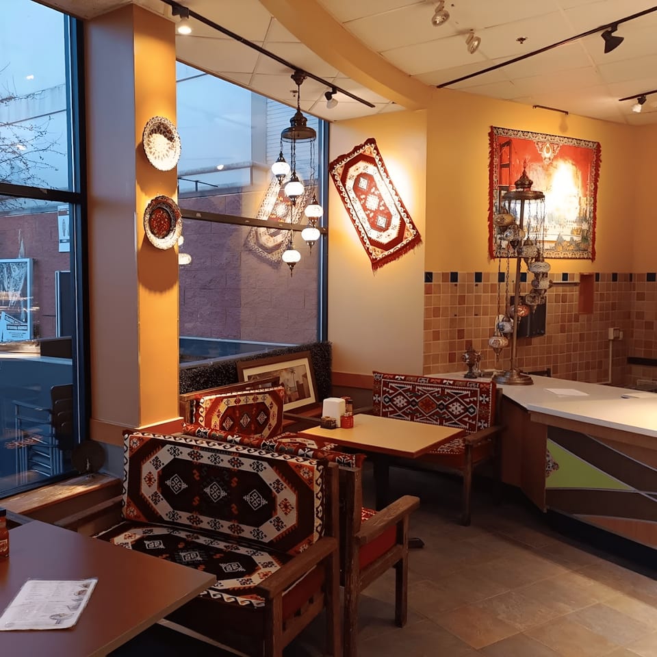 Interior of Kebab House/Mozaic Cafe, featuring Turkish rugs, patterned seating, and hanging lamps.